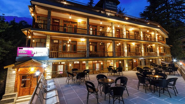 A two-story hotel with a reception area, outdoor seating, and a sign indicating it is a holiday home. - Vivaan Stay Holiday Home international (Manali)