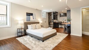 A modern bedroom with a large bed, a desk, and a staircase leading to an upper level. - 4BR House | City Views | Balconies | Walk to OTR (Cincinnati)
