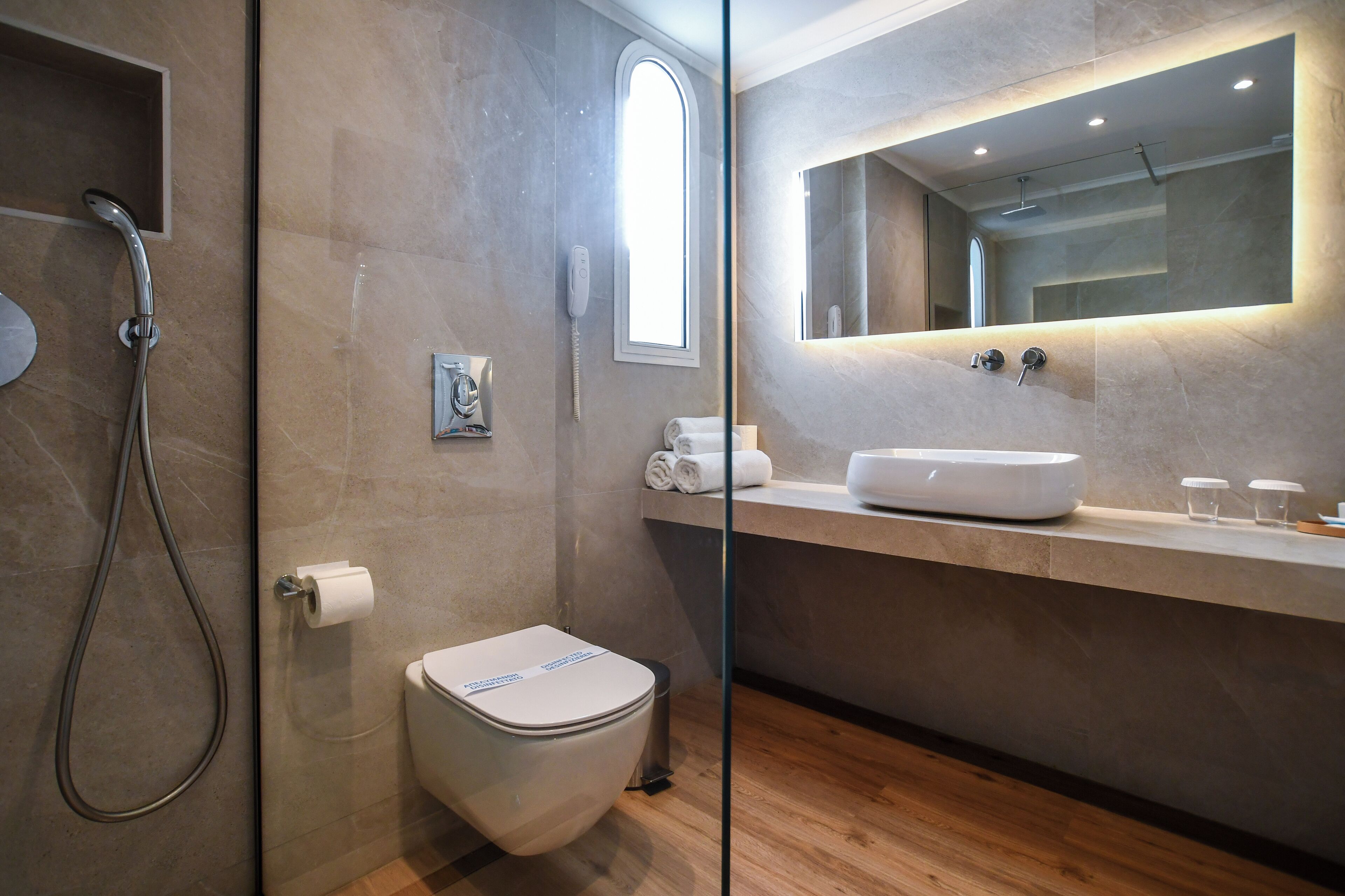 Une salle de bain moderne équipée d’une douche, de toilettes et d’un meuble-lavabo avec un miroir.
