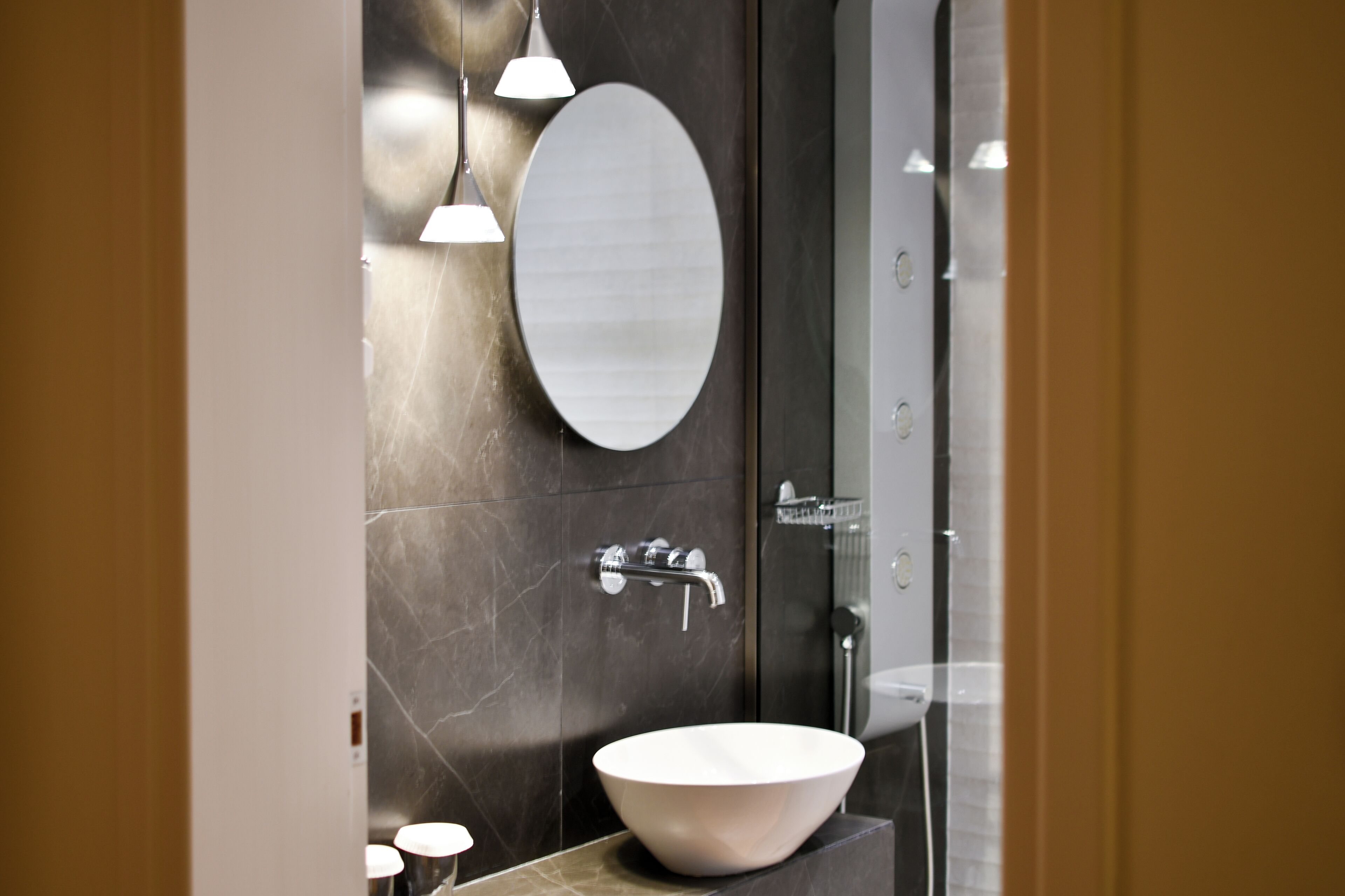 A modern bathroom with a large oval mirror, a vessel sink, and a shower area.