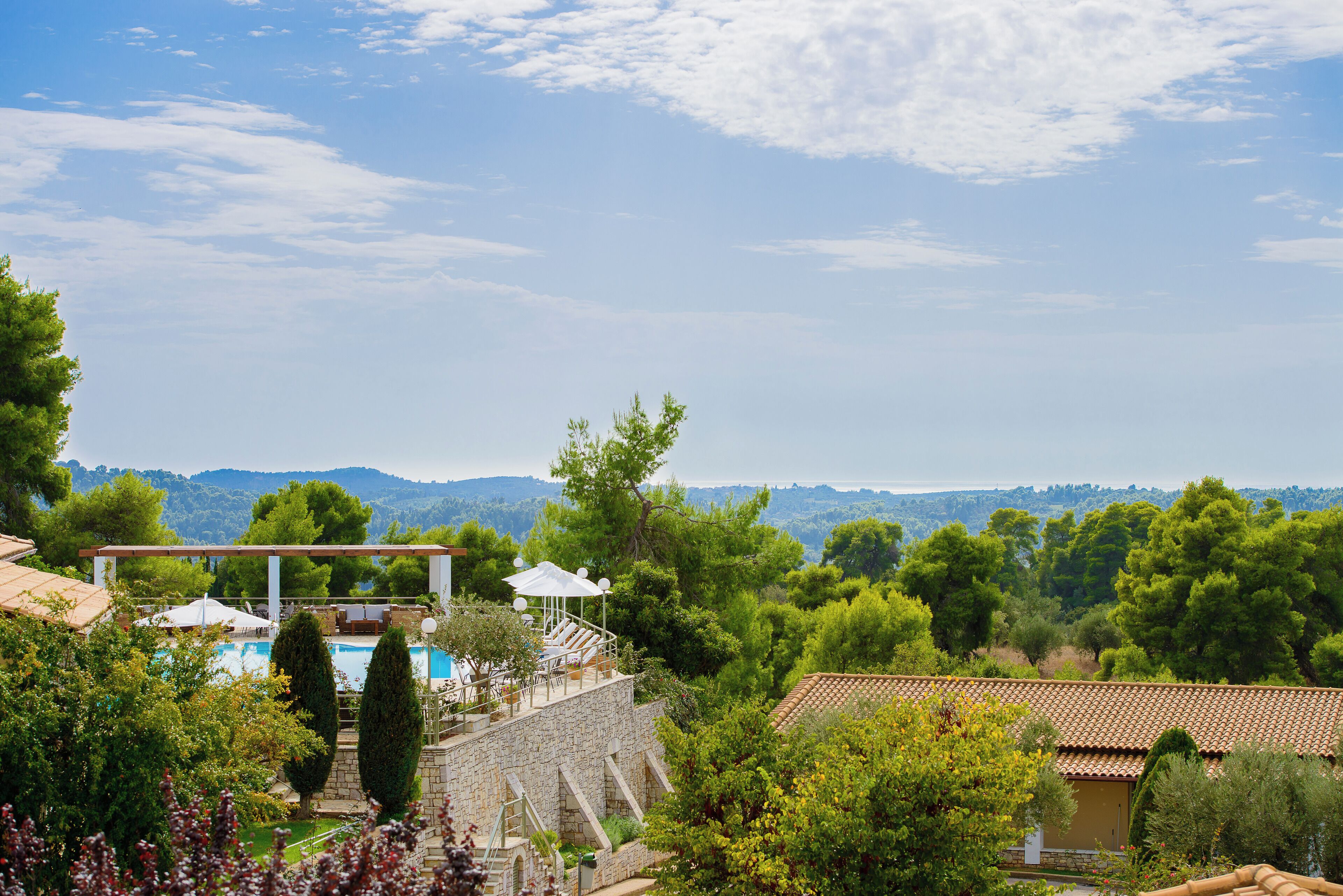 A stone villa with a pool, outdoor seating, and a view of the surrounding hills.