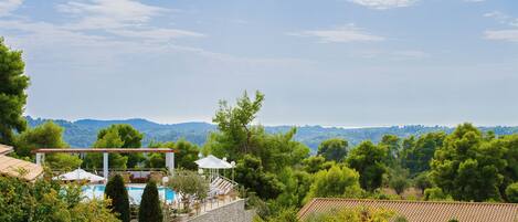 A stone villa with a pool, outdoor seating, and a view of the surrounding hills.