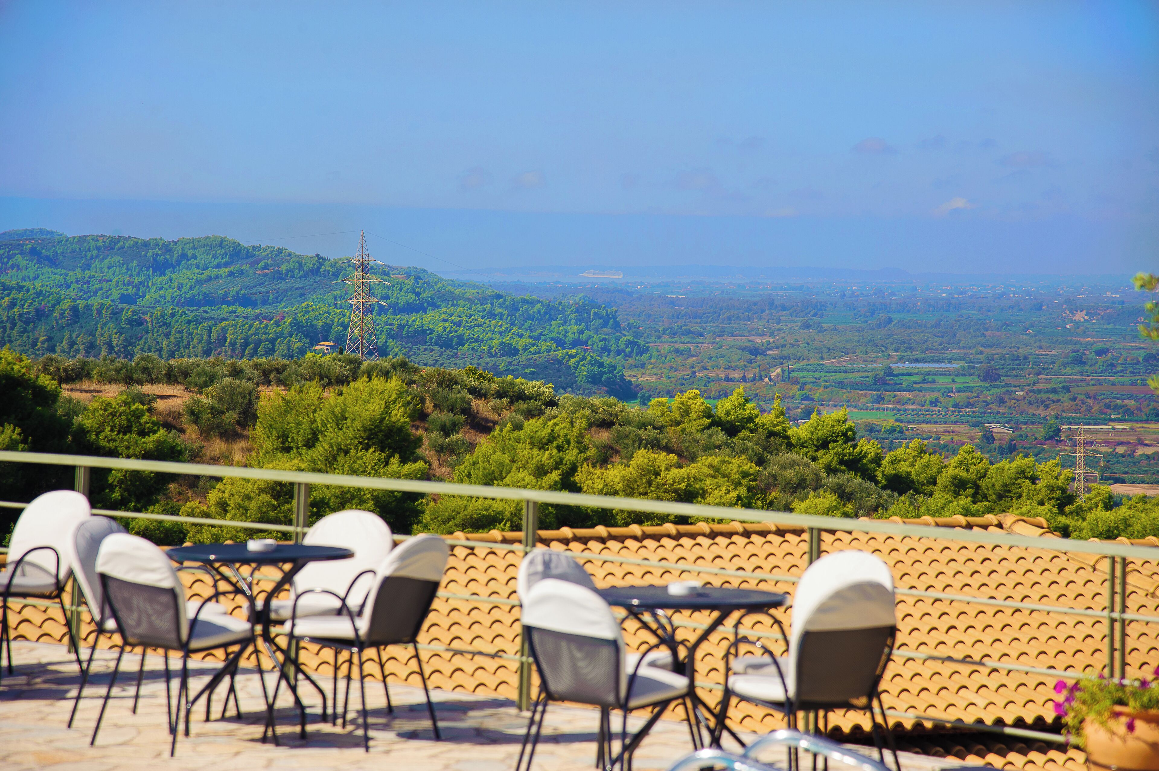 Una terraza con asientos al aire libre y una vista panorámica de un paisaje montañoso.