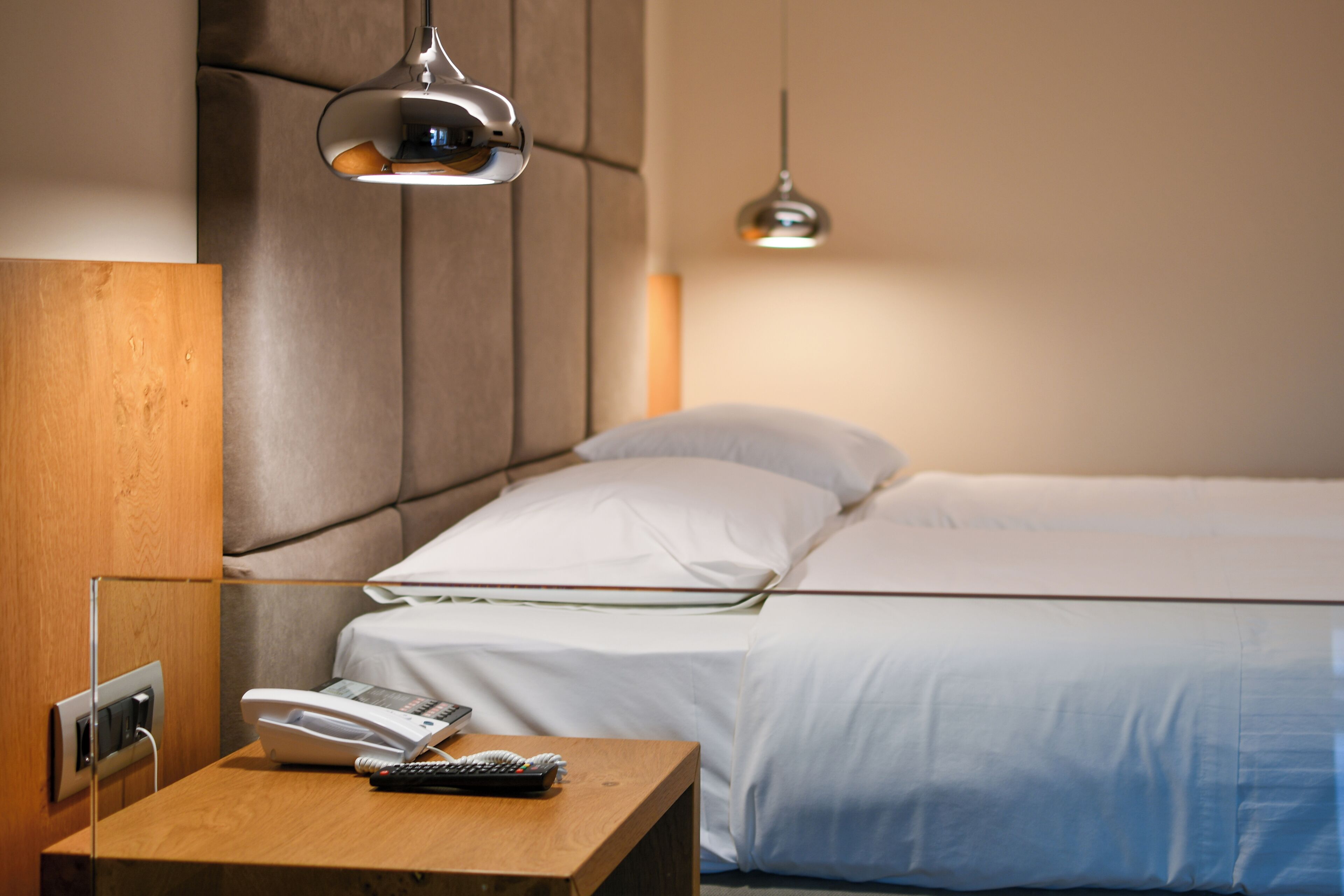 Een hotelkamer met een bed, nachtkastje en telefoon.