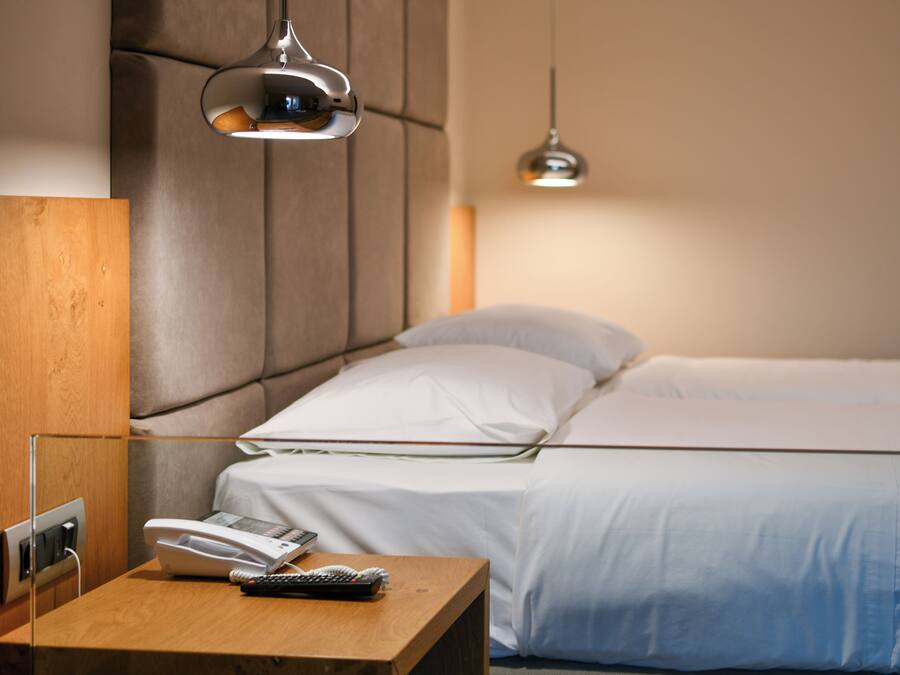 Een hotelkamer met een bed, nachtkastje en telefoon.