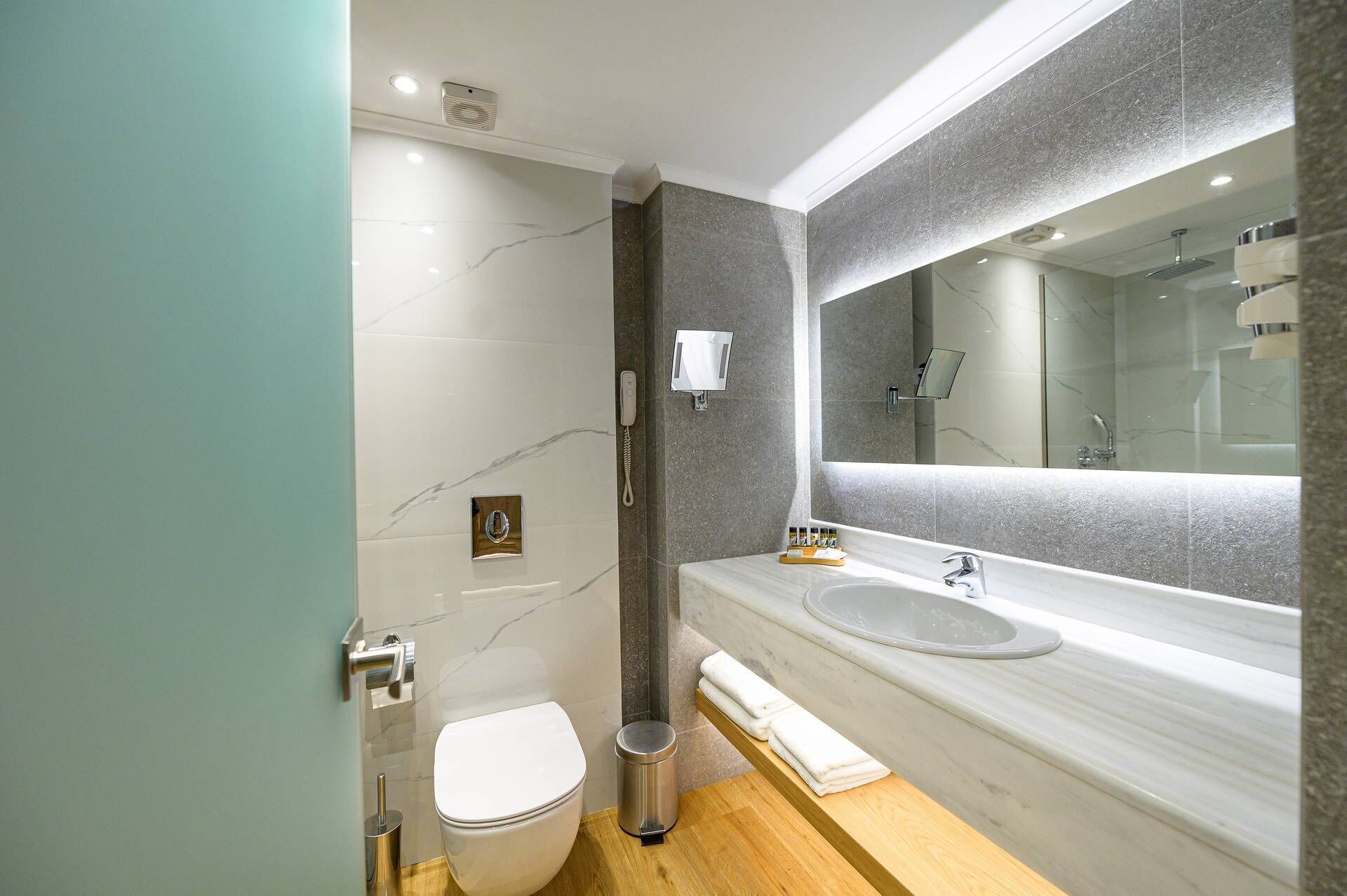 Une salle de bain moderne avec un meuble-lavabo en marbre, un grand miroir, des toilettes et un espace douche.
