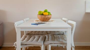 Een eettafel met een houten schaal vol fruit, een tijdschrift en comfortabele stoelen.