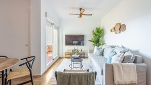 A modern living room with a sofa, a coffee table, a TV, and a ceiling fan.