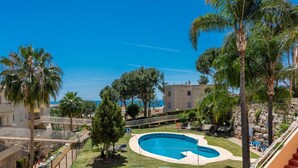 A pool area with two circular pools, surrounded by palm trees and a clear blue sky.