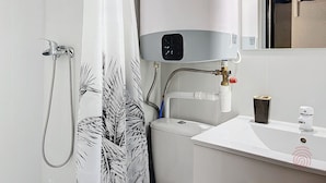 A bathroom with a shower, a toilet, and a sink.