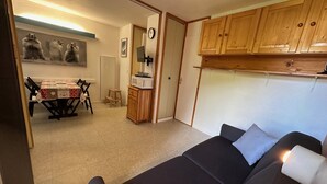 A compact living space with a sofa, a dining table with chairs, a microwave, and wooden cabinets. - Divisible studio, southwest balcony, quiet, 24m² (La Plagne Montchavin Les Coches)