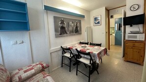 A compact kitchen with a microwave, a clock, and a framed picture on the wall. - Divisible studio, southwest balcony, quiet, 24m² (La Plagne Montchavin Les Coches)