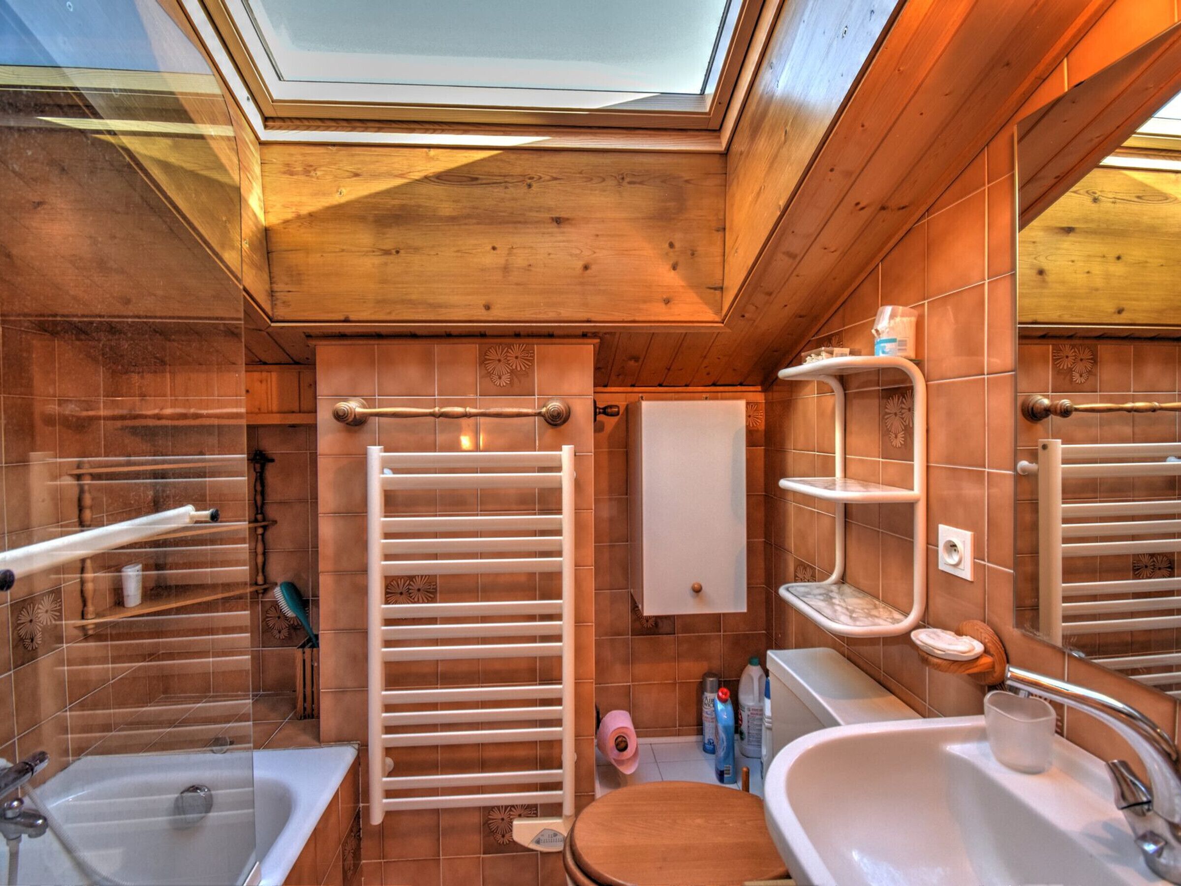 A compact bathroom with a skylight, a bathtub, a toilet, and a sink.