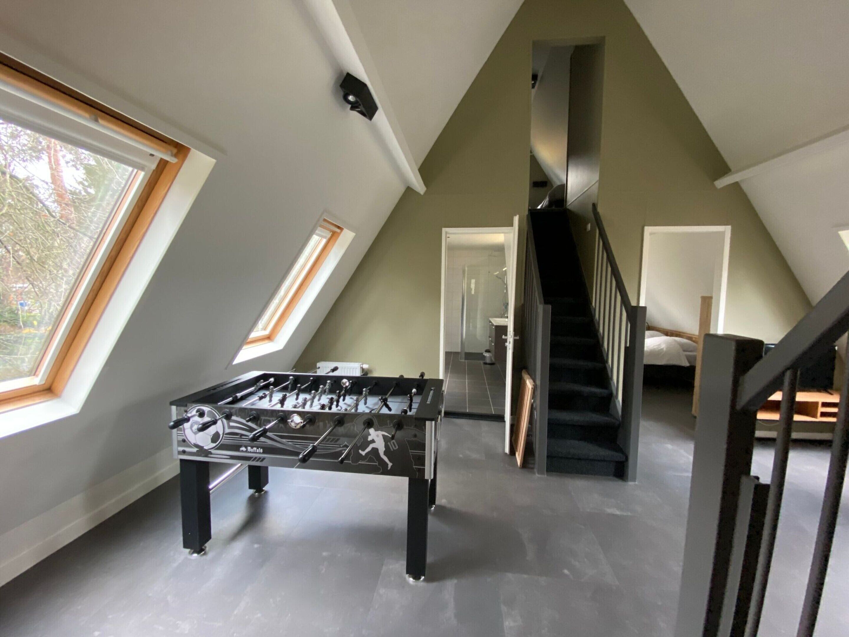 Ein geräumiger Lofts mit Kicker, einer Wendeltreppe und großen Fenstern.