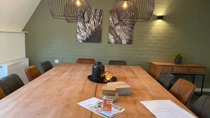 A conference room with a large wooden table, leather chairs, and modern pendant lighting. - Holiday Home Near Biesbosch National Park (Oosterhout)