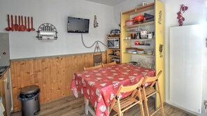 A compact kitchen with a wooden wall, a table with a red tablecloth, and a microwave. - Studio in Morzine, near slopes, balcony, parking, 4 pers (Morzine)