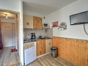 A compact kitchen with wooden cabinets, a stove, a sink, and a trash bin. - Studio in Morzine, near slopes, balcony, parking, 4 pers (Morzine)
