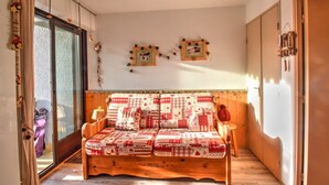 A cozy room with a wooden bed, a sliding glass door, and a small table with a lamp. - Studio in Morzine, near slopes, balcony, parking, 4 pers (Morzine)