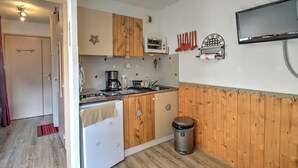 A compact kitchen with wooden cabinets, a built-in oven, a coffee maker, and a trash bin. - Studio in Morzine, near slopes, balcony, parking, 4 pers (Morzine)
