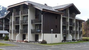 A multi-story hotel with balconies, a parking lot, and a mountainous backdrop. - Studio in Morzine, near slopes, balcony, parking, 4 pers (Morzine)