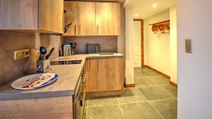 A compact kitchen with wooden cabinets, a small countertop, and a tiled floor. - Chalet in Morzine for 10 people, parking, wifi (Morzine)