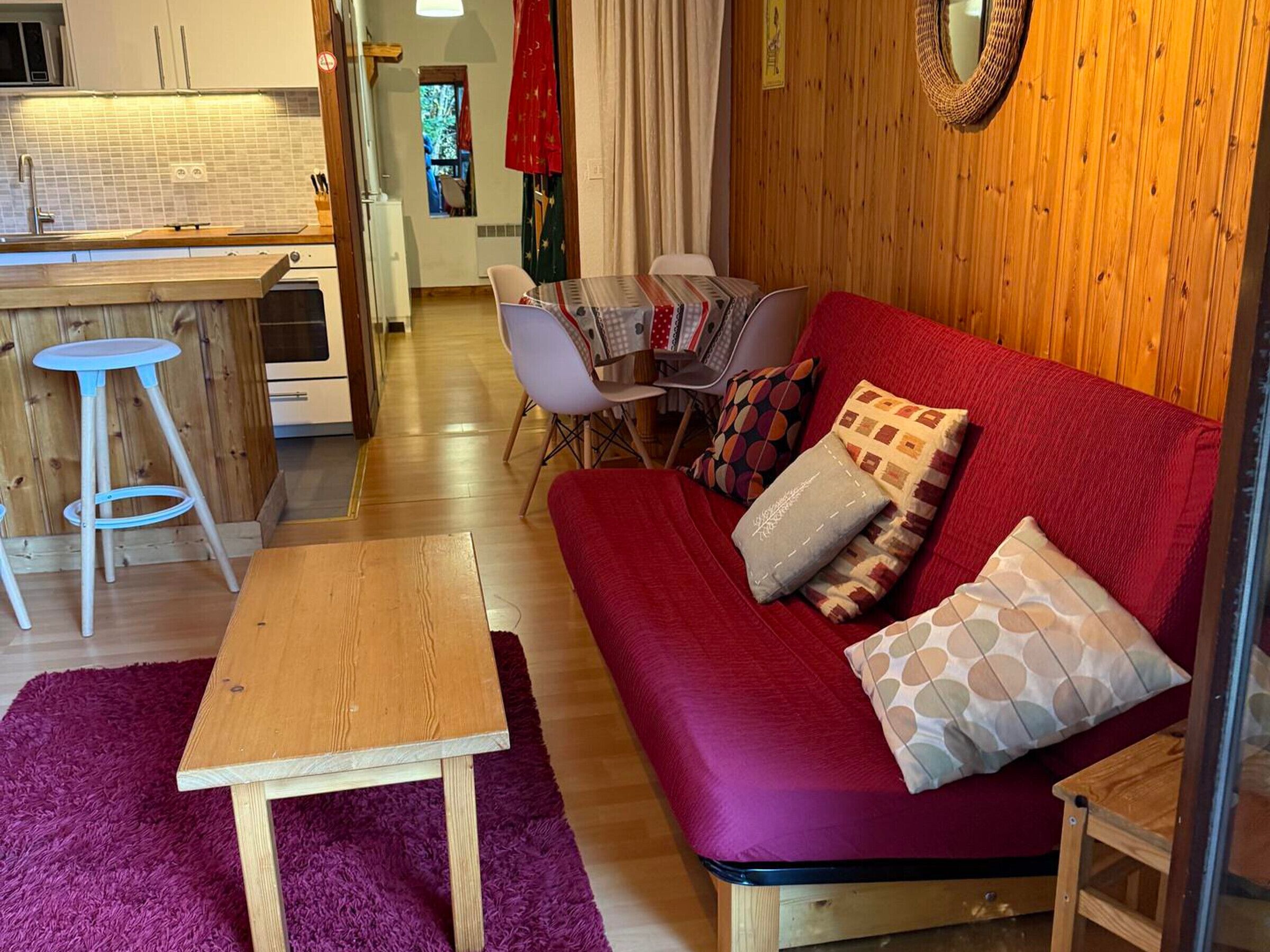 A cozy living room with a red sofa, a wooden coffee table, and a purple rug.