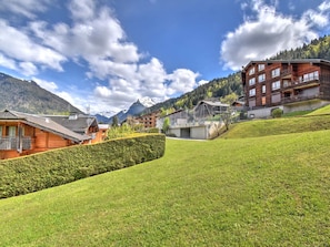 A mountainous village with wooden houses, a large building with balconies, and a clear sky.