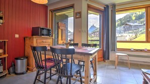 Una cocina acogedora con una mesa de comedor, sillas y un microondas. Se ve una ventana con vistas a una montaña y edificios.