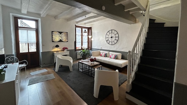 Un grand espace de vie comprenant un escalier, un canapé, une table à manger et une plante en pot.