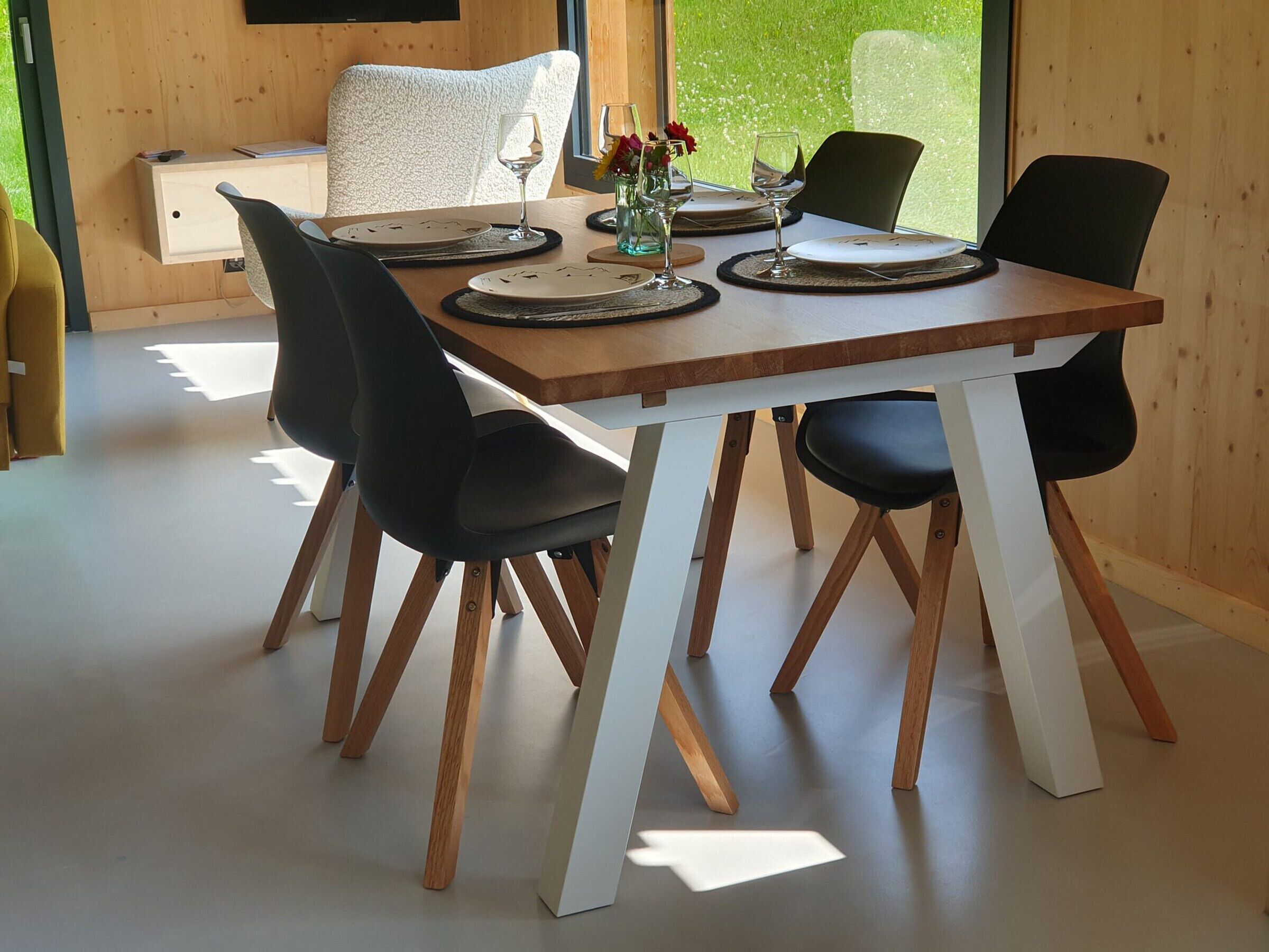 Comedor con mesa de madera dispuesta para cuatro personas, rodeado de sillas negras.