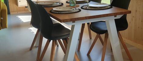 Comedor con mesa de madera dispuesta para cuatro personas, rodeado de sillas negras.