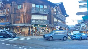 Ein mehrstöckiges Holzgebäude mit Balkonen, ein Geschäft im Erdgeschoss und Autos vor der Tür.
