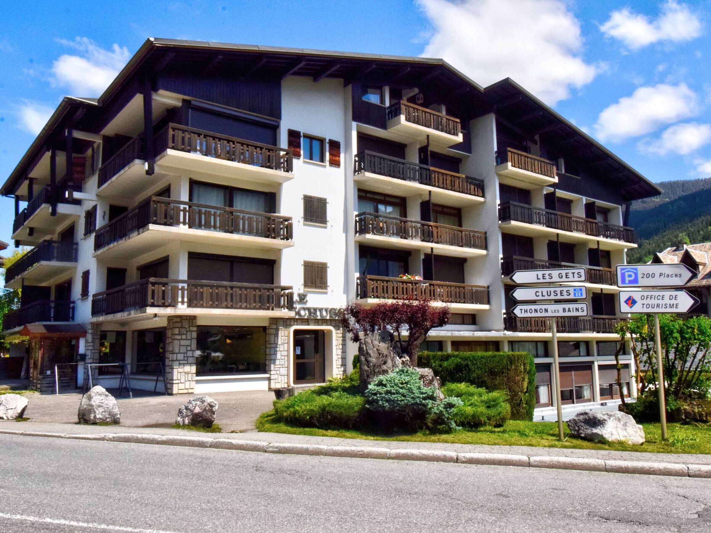 A multi-story hotel with balconies, a sign indicating 200 parking places, and a sign for the office of tourism.
