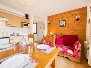 Una camera accogliente con una parete in legno, un tavolo da pranzo per due persone e un divano rosso.