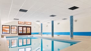 Een zwembad met helder water, omgeven door betegelde vloeren en muren.