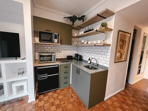 Una cocina compacta con microondas, tostadora, lavamanos y armarios.