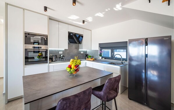 A modern kitchen with a central island, stainless steel appliances, and a large refrigerator. - Gorgeous home in Vrana (Vrana)