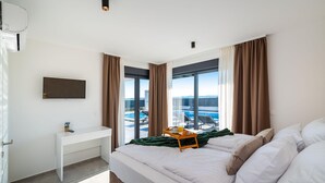 Ett hotellrum med en säng, ett skrivbord och utsikt över en pool och berg.