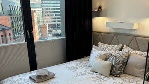 Habitación de hotel con una cama grande, vistas a la ciudad y un diseño moderno.