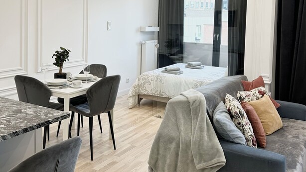 Una habitación de hotel moderna con comedor, una cama con vistas y un rincón de descanso.