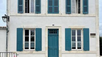 Un immeuble de deux étages avec des volets bleus, une porte centrale et une enseigne indiquant « Boulevard Thiers ».