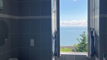 Une salle de bain avec vue sur la mer, un lavabo et un miroir.