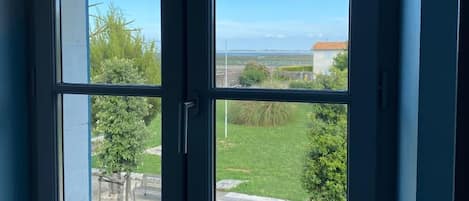 A window with a view of a grassy area and a building in the distance.