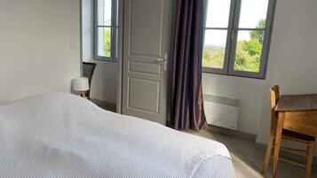 Une chambre à coucher avec un lit, une chaise, un bureau et une fenêtre avec des rideaux.