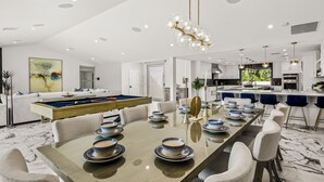 Un espace de restauration moderne avec une longue table dressée pour six personnes, entourée de chaises blanches.