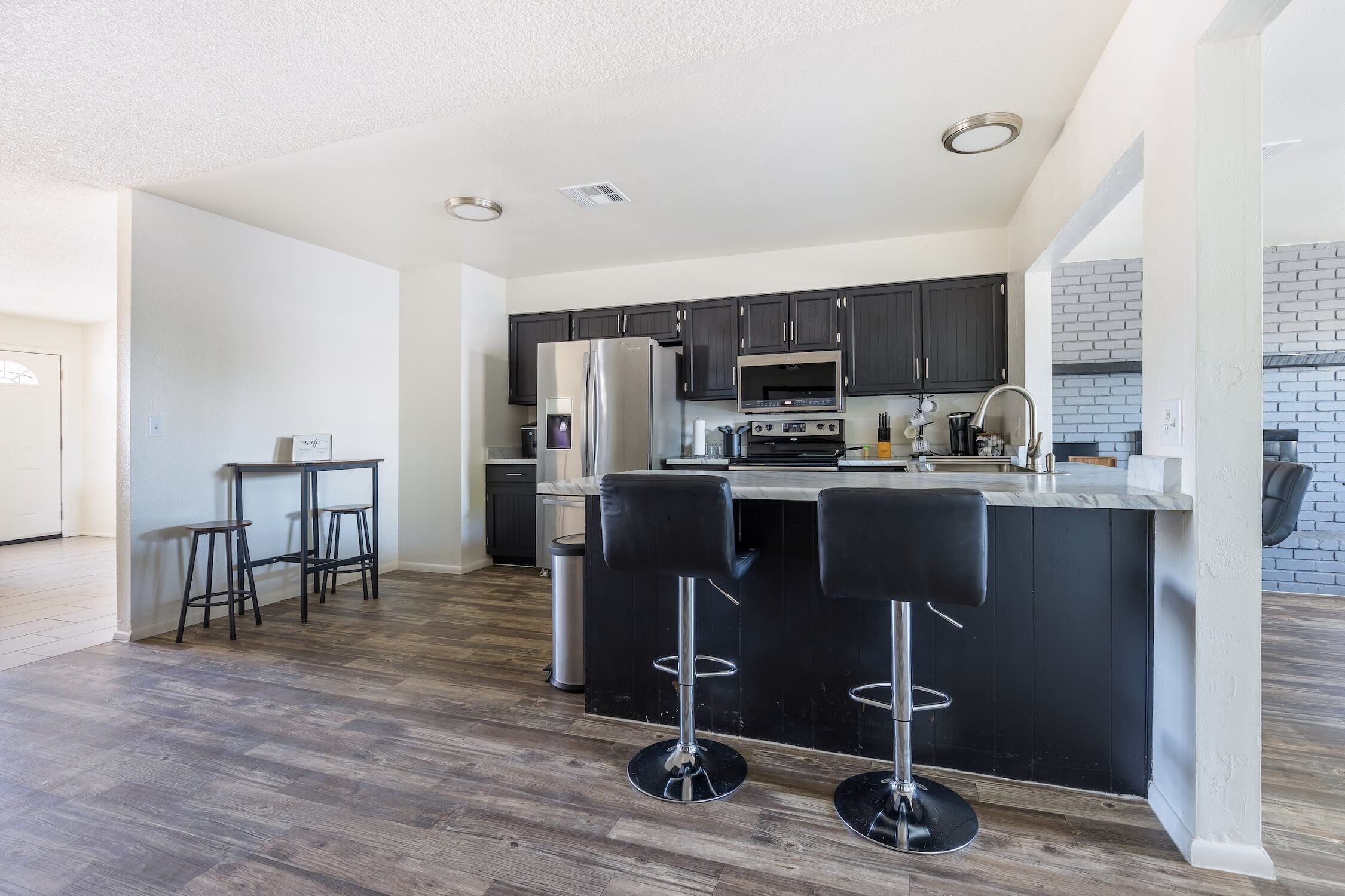 A modern kitchen with dark cabinets, stainless steel appliances, and a central island with bar stools.