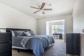 Een slaapkamer met een bed, bureau, stoel en een kledingkast.