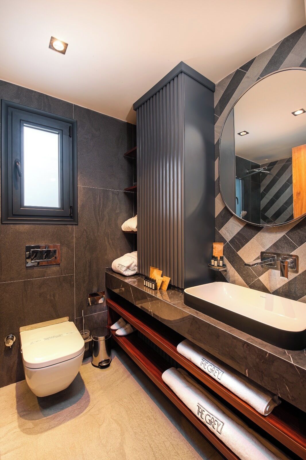 A modern bathroom with a large mirror, a toilet, and a vanity with a sink.