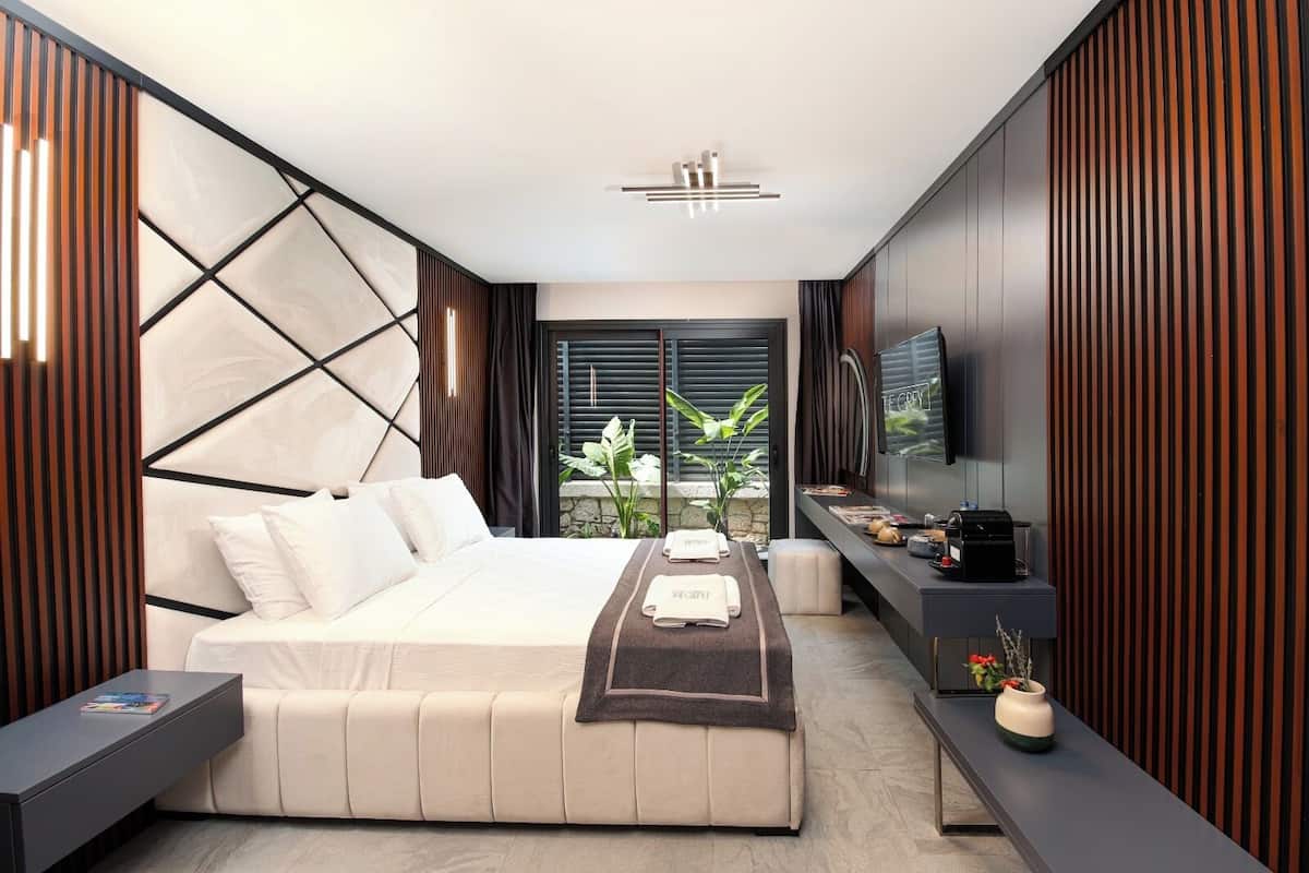 Camera da letto moderna con un letto, comodino, televisione e vista sul verde.
