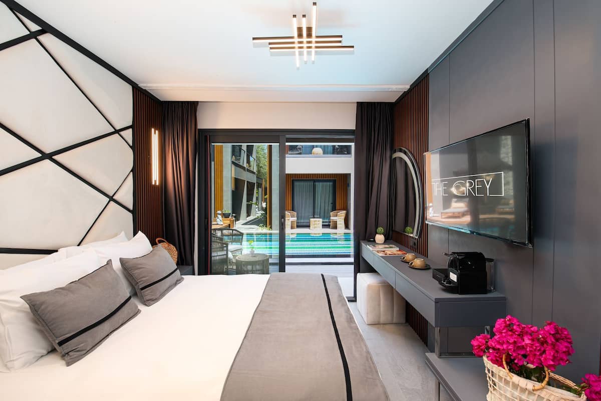 Una moderna camera d'albergo con un letto, una TV, un tavolino consolle e vista su una piscina all'aperto.
